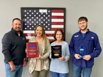 Buffington Brothers leadership team holding Carrier President's Award and Carrier Factory Authorized Dealer plaques in front of an American flag.