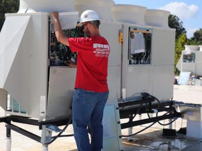 Technician in Buffington Brothers uniform servicing a large rooftop HVAC unit.