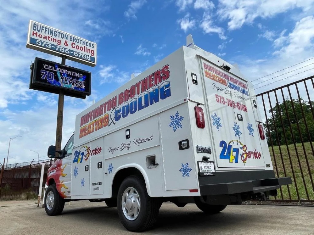Buffington Brothers Heating & Cooling box truck parked beneath a sign celebrating 70 years in Poplar Bluff.