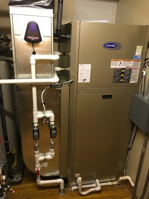 Completed Carrier residential system installation with clean condensate and water piping in a utility closet.