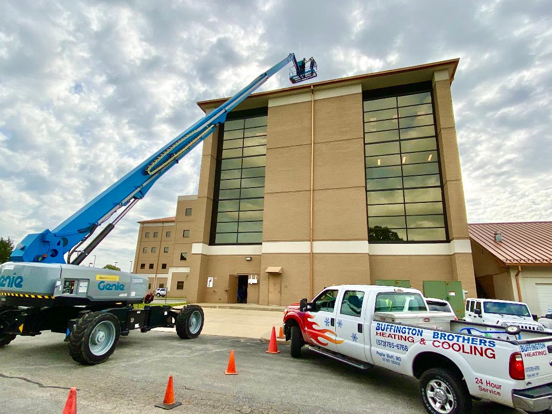 Buffington Brothers service truck and boom lift reaching the upper floors of a multi-story commercial building.